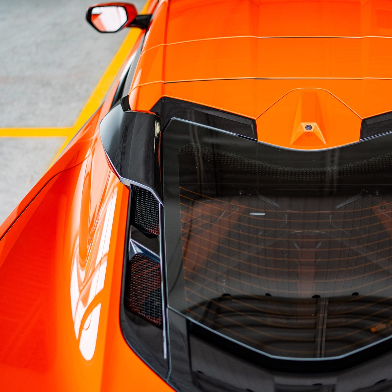 Top-down view of a Carbon Flash Metallic Black ACS C8 RQ Intake Port installed on a Sebring Orange C8 Corvette